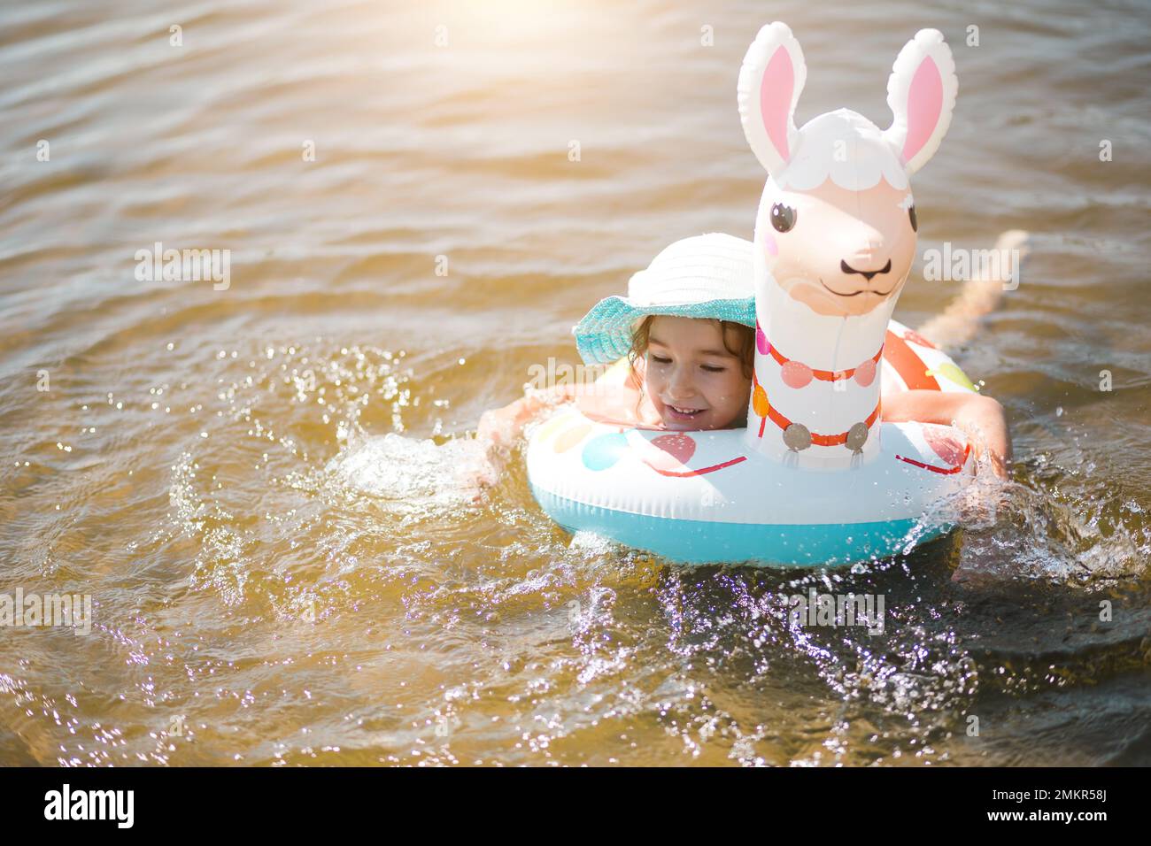 Fille dans un chapeau il se tient sur la rive avec un cercle gonflable en  forme de lama. Alpaga gonflable pour un enfant. Mer avec un fond  sablonneux. Beach Holi Photo Stock -