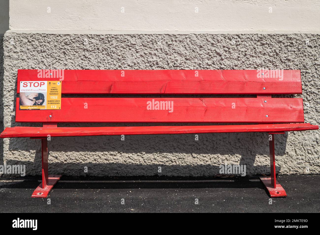 Un banc peint en rouge pour la Journée internationale pour l'élimination de la violence à l'égard des femmes dans la rue de Mezzolago, vallée de Ledro, Trento, Italie Banque D'Images