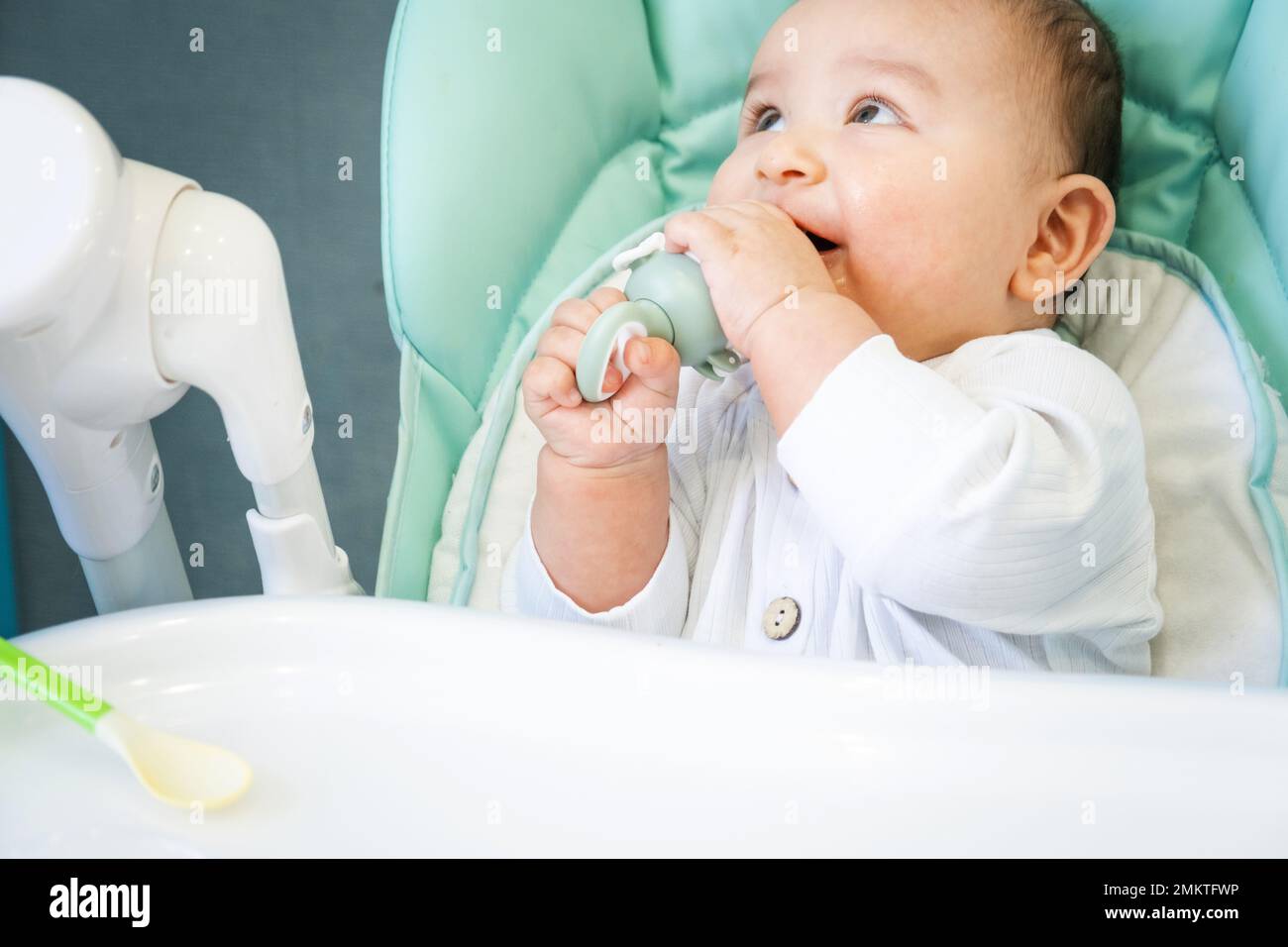 Un bébé heureux et content mange une purée de banane d'une mamelon. Introduction d'aliments complémentaires, d'aliments sains pour bébé, l'alimentation du bébé à la table Banque D'Images