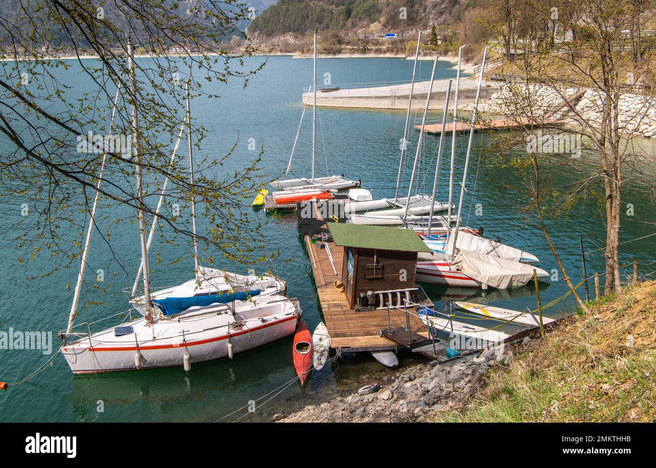 Le lac de Ledro (vallée de Ledro) et les montagnes environnantes lors d'une journée de printemps claire. Une étape d'atterrissage en bateau et quelques bateaux. Province de Trento, Trentin-Haut-Adi Banque D'Images