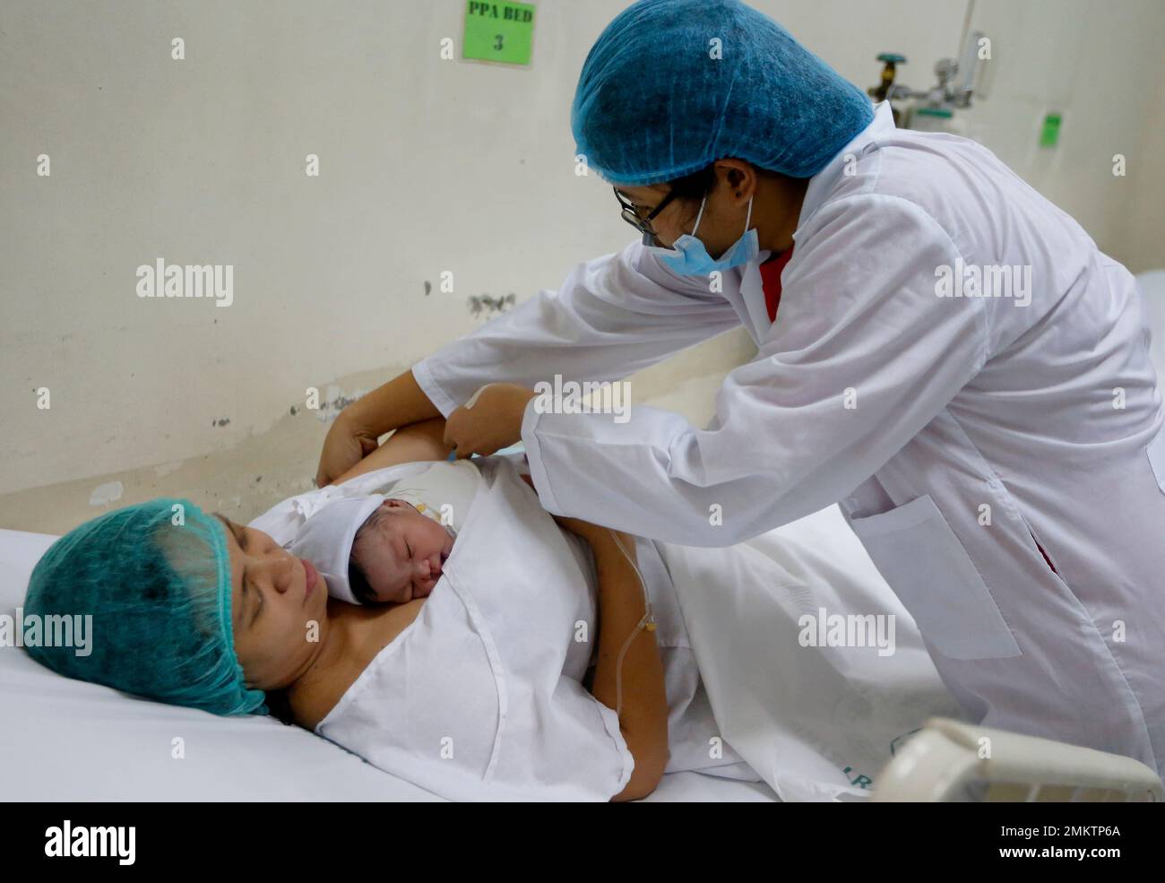 A doctor tends to mother Leni Bonto and baby Zairah inside the recovery room after Zairah was born on New Year's day Tuesday, Jan. 1, 2019 at Fabella Children's Hospital in suburban Quezon city northeast of Manila, Philippines. Zairah, the third child of Bonto, became the first baby born at the hospital on New Year's day. (AP Photo/Bullit Marquez) Banque D'Images