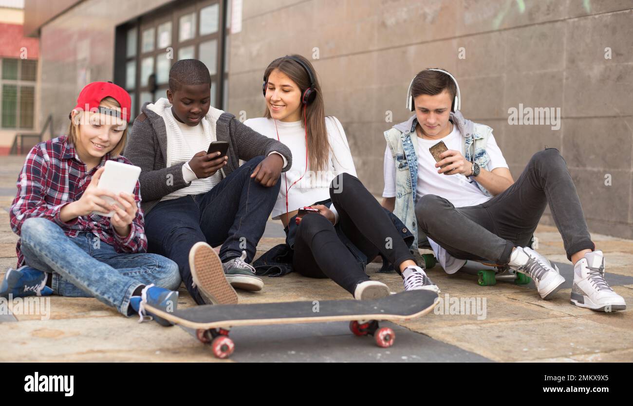 les adolescents multinationaux jouent dans les smartphones dans la cour d'école Banque D'Images