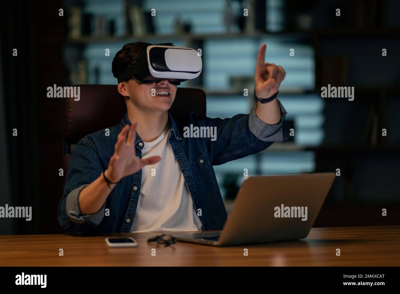 Homme d'affaires utilisant un ordinateur portable et un casque VR sans fil au bureau Banque D'Images