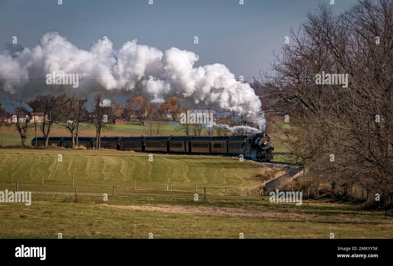 Vue sur un train de passagers antique approchant, soufflant de la fumée et de la vapeur, le jour de l'automne Banque D'Images