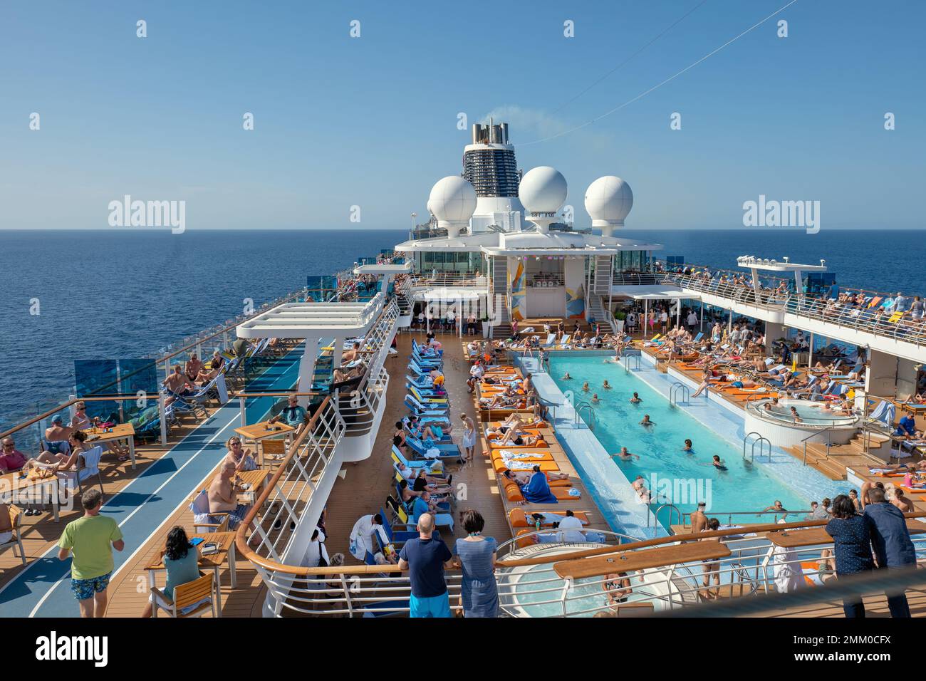 Bateau de croisière en mer, avec de nombreux vacanciers à la piscine. Banque D'Images