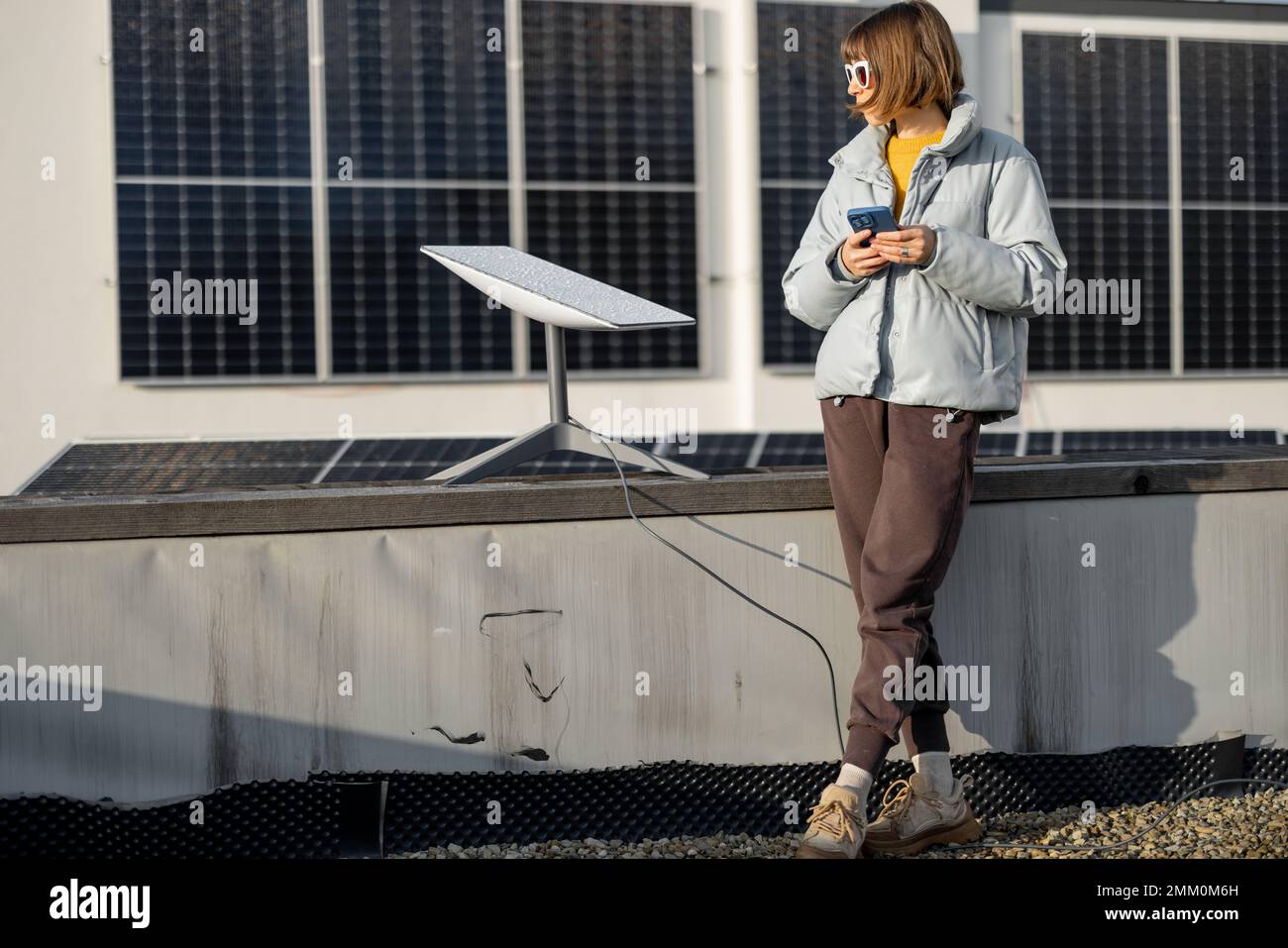 Femme utilise Starlink Internet sur le toit avec panneaux solaires Banque D'Images