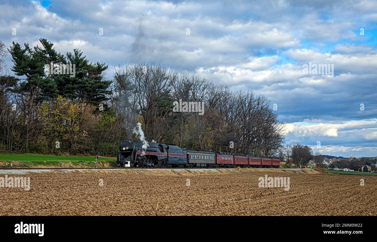 Voir os un train de voyageurs à vapeur classique passant lentement les champs de maïs récoltés le jour de l'automne Banque D'Images