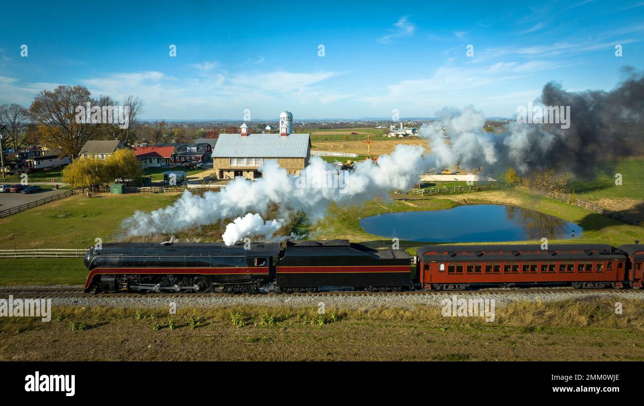 Vue aérienne parallèle d'un train de passagers à vapeur antique restauré qui se déplace à travers la campagne lors d'une Sunny automne Banque D'Images