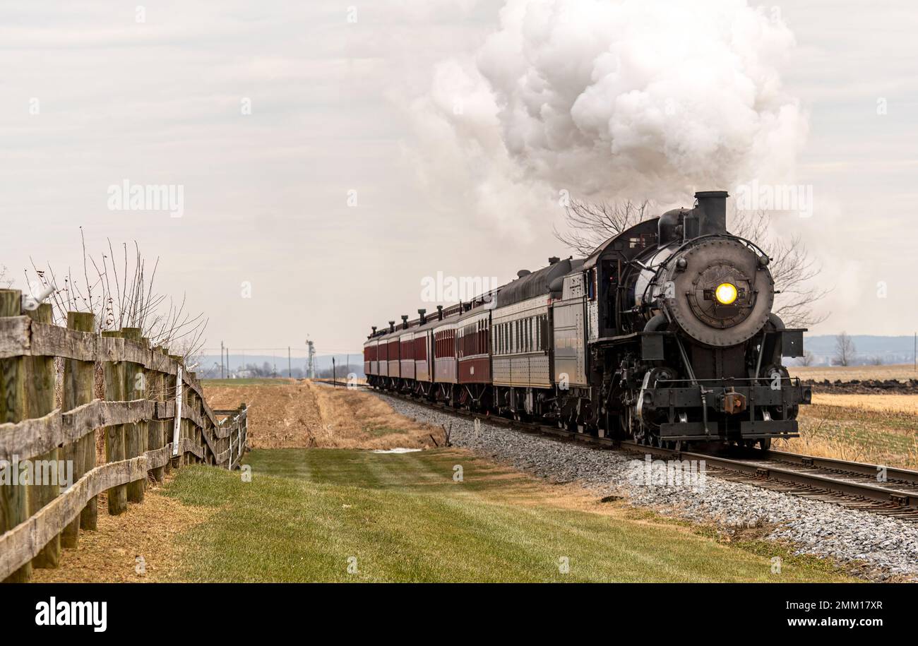 Vue sur un train de passagers à vapeur classique qui s'approche, traversant la campagne, le jour d'hiver Banque D'Images