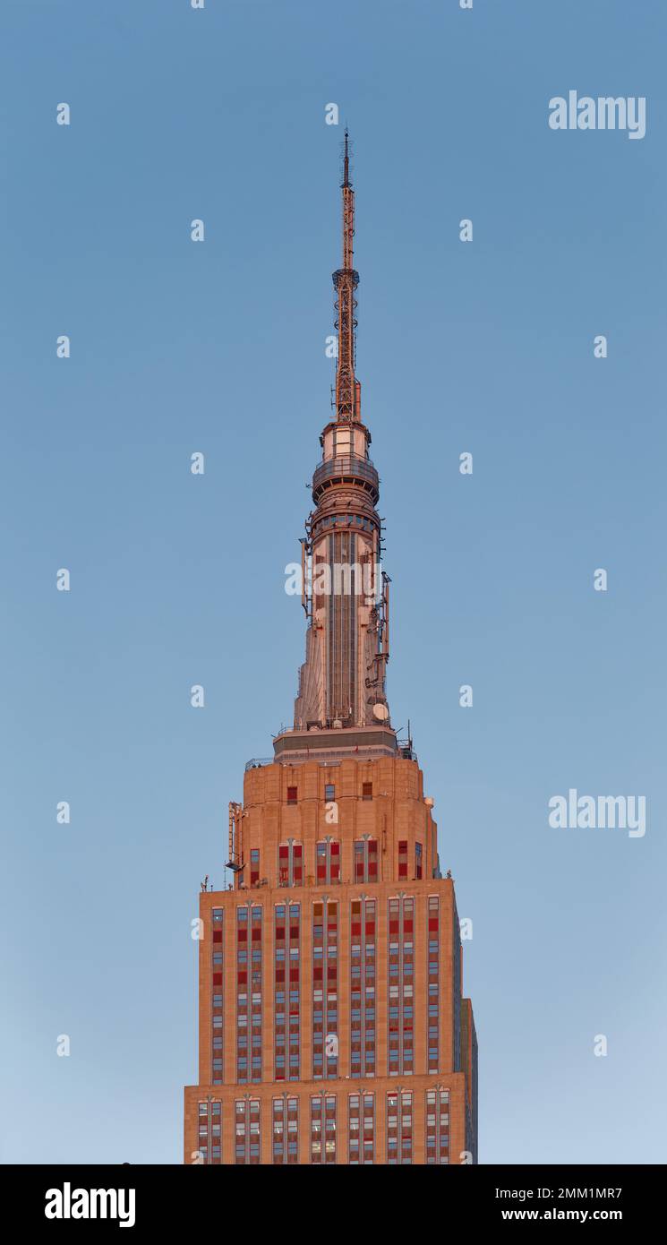 NYC : la façade est de l'Empire State Building passe du gris au rouge doré à l'aube, lorsque le soleil est à son point le plus bas. Banque D'Images