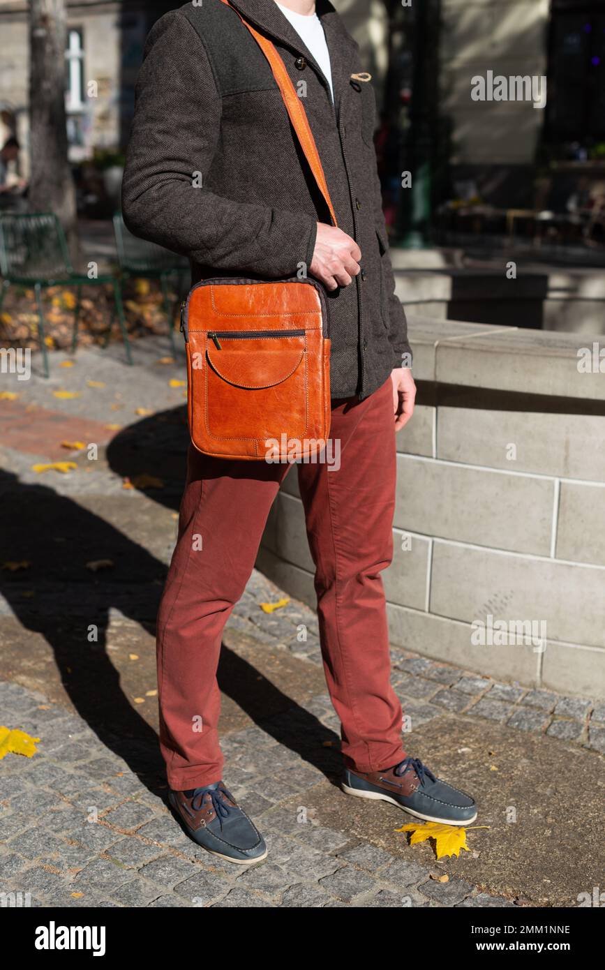 photo en gros plan du sac en cuir de messanger orange sur l'épaule de l'homme Banque D'Images