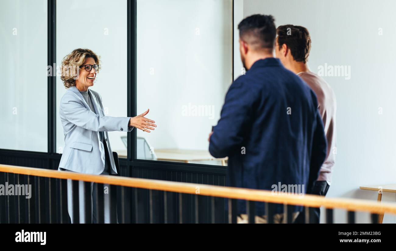 femme d'affaires tend la main pour une poignée de main alors qu'elle rencontre ses nouveaux partenaires. Professionnelle féminine heureuse établissant des liens avec des associés d'affaires. Busin Banque D'Images