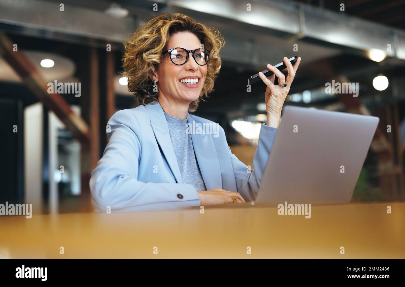 Femme professionnelle parlant sur un téléphone mobile dans un bureau. Une heureuse femme d'affaires ayant une discussion téléphonique avec ses associés. Entreprise mature W Banque D'Images