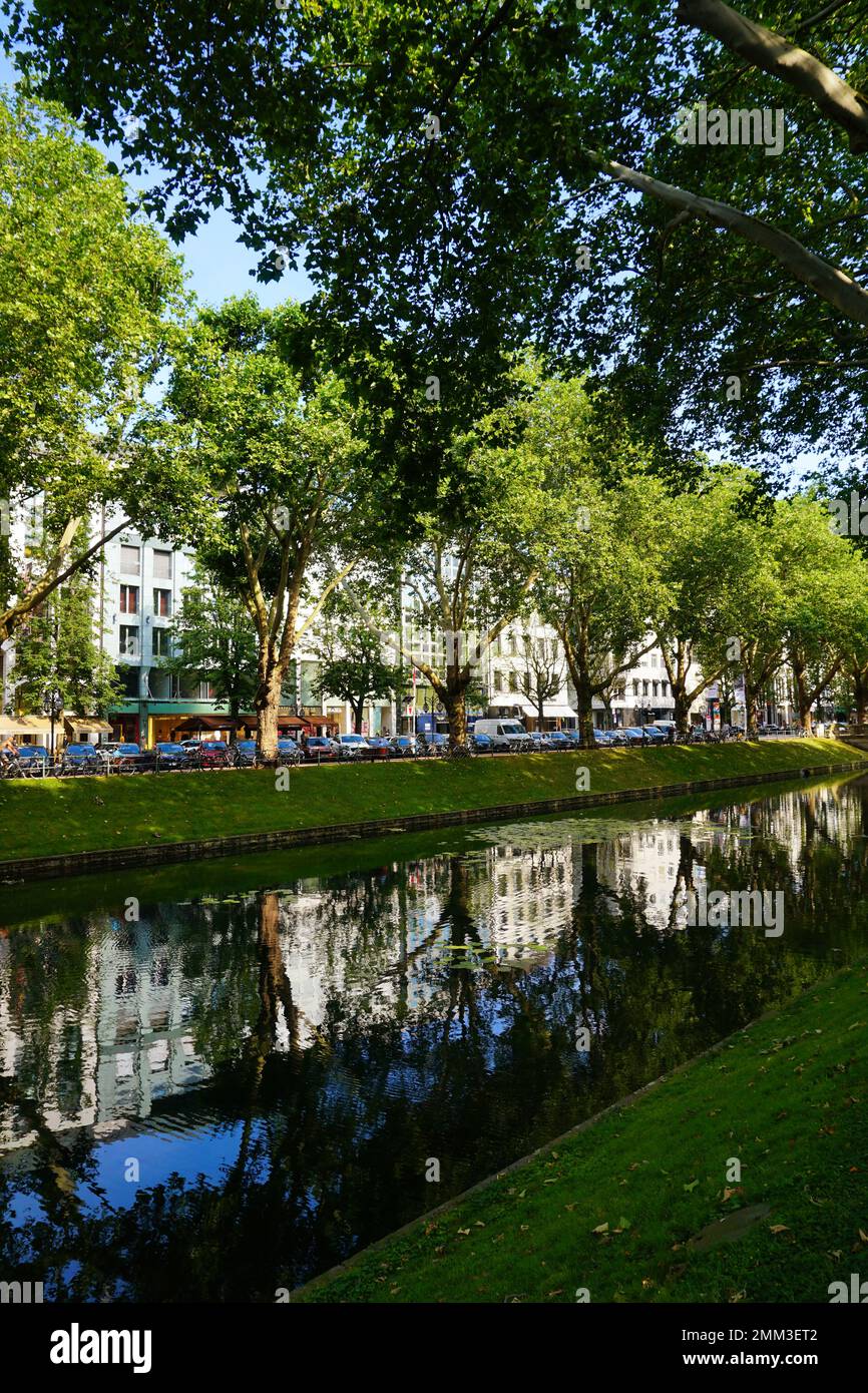 Le boulevard commerçant Königsallee à Düsseldorf : vue sur le canal vert de la ville 'Kö-Graben' du 'côté calme' au 'côté animé' avec de nombreux magasins. Banque D'Images