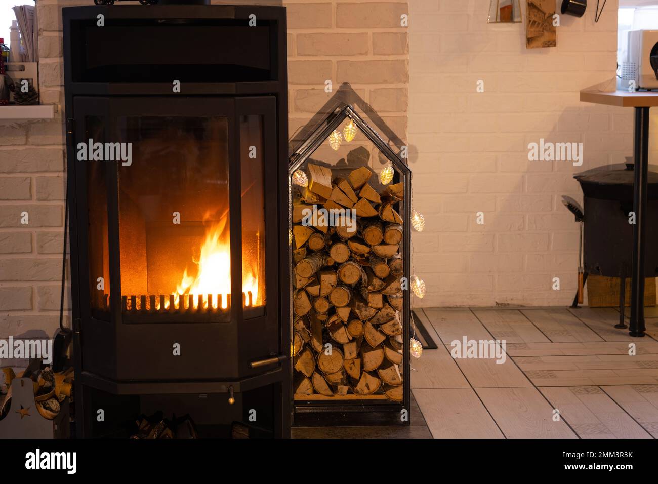 Poêle en métal noir cheminée avec bois dans une pile de bois - l'intérieur d'une maison de village privée. Chauffage et chauffage de la maison avec bois de chauffage, l'hea Banque D'Images