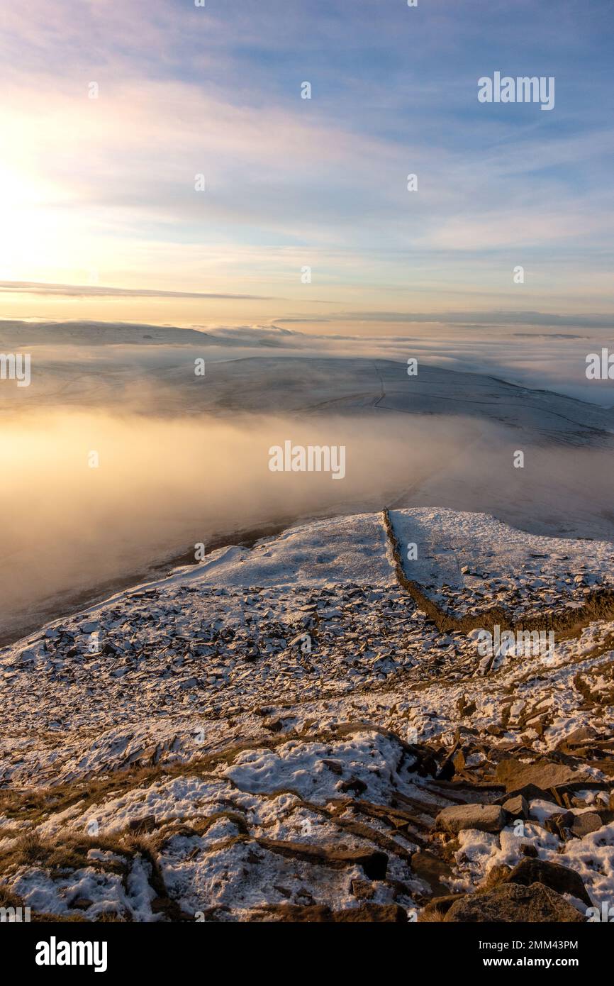 En regardant le dernier sentier enneigé depuis la crête du sommet de la montagne de Pen-y-ghent au lever du soleil avec la brume et la neige dans le parc national de Yorkshire Dales, en Banque D'Images