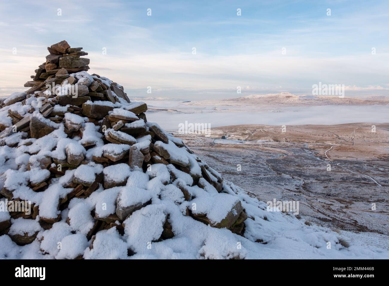 Cairn enneigé au sommet de la montagne de Pen-y-ghent, montrant le chemin vers le bas mis en évidence par la neige sur les sentiers, parc national de Yorkshire Dales, Royaume-Uni Banque D'Images