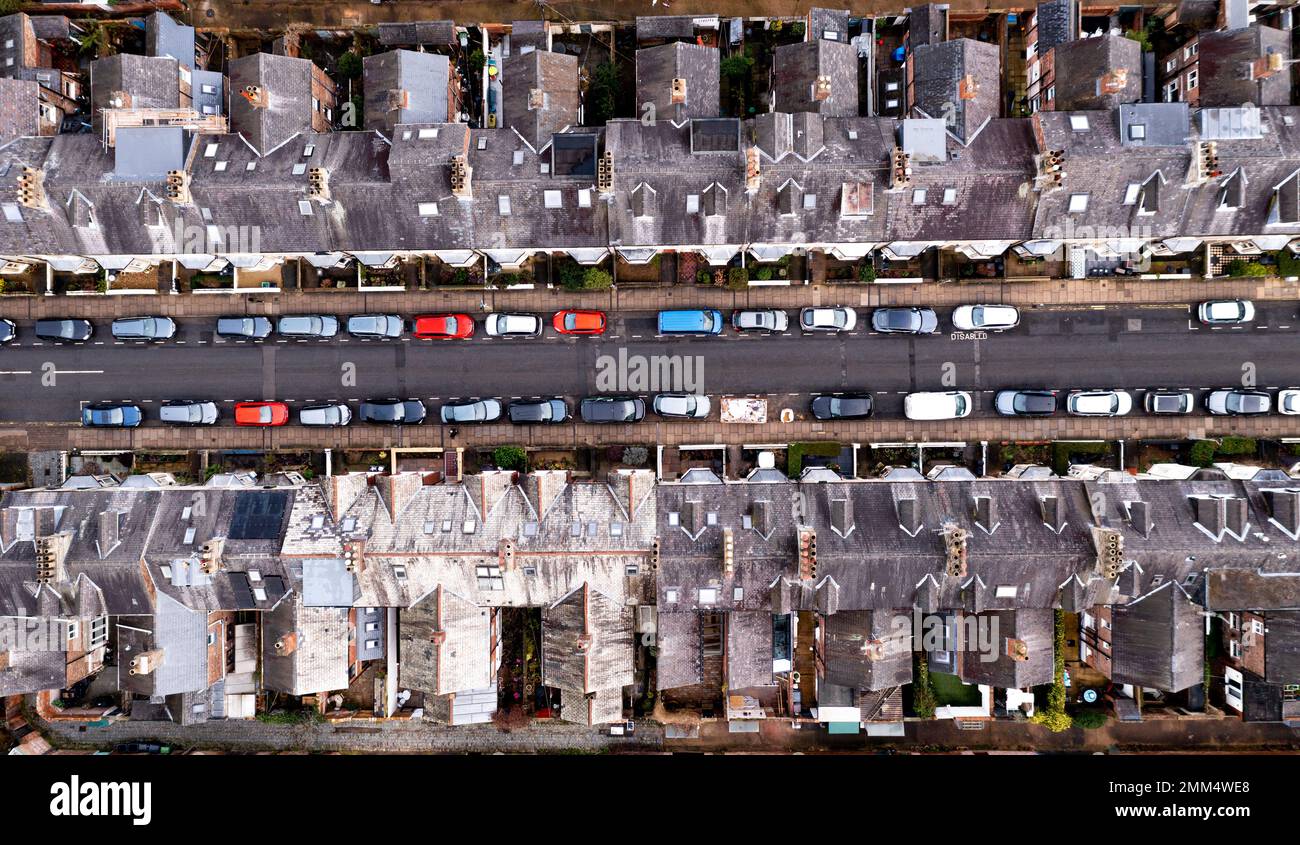 Une vue aérienne directement au-dessus des toits de maisons mitoyennes dos à dos sur une rue de banlieue droite avec des voitures garées bordant la route Banque D'Images