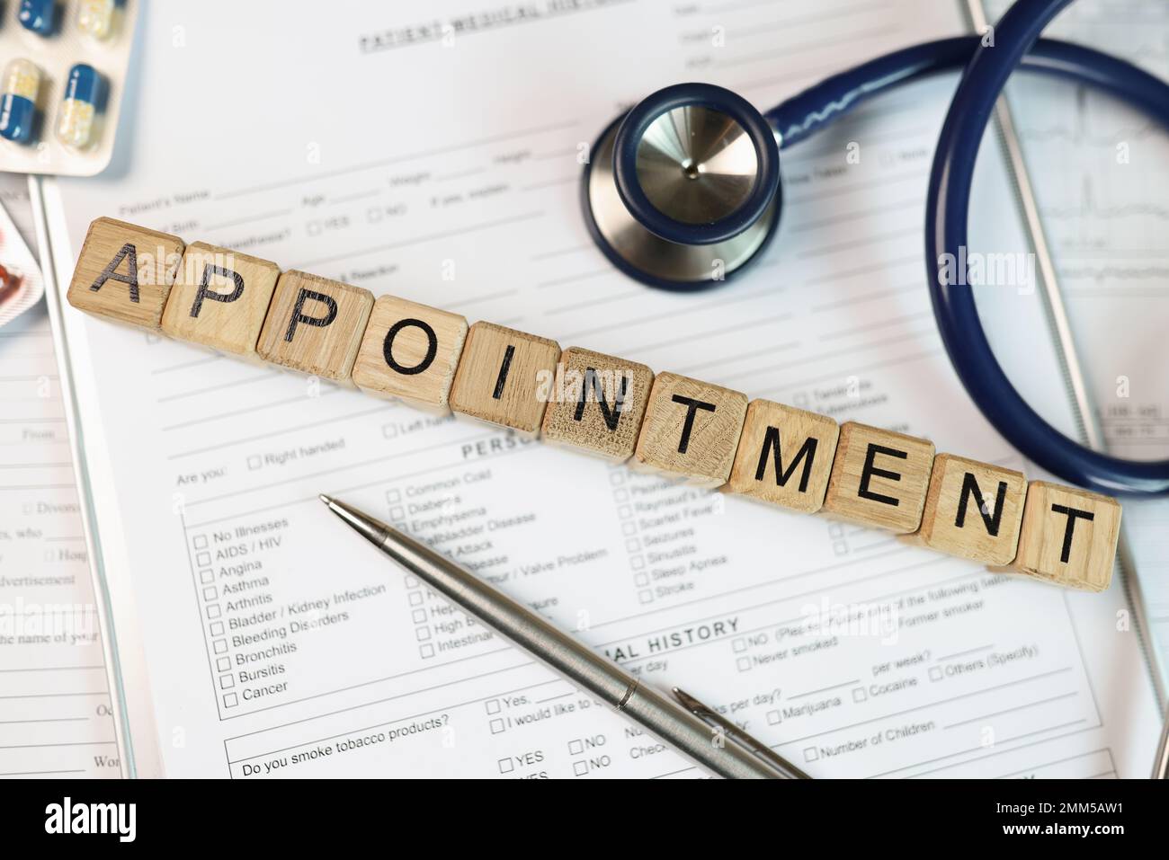 Rendez-vous de mot recueilli à partir de cubes en bois sur des documents médicaux avec stéthoscope et pilules. Banque D'Images