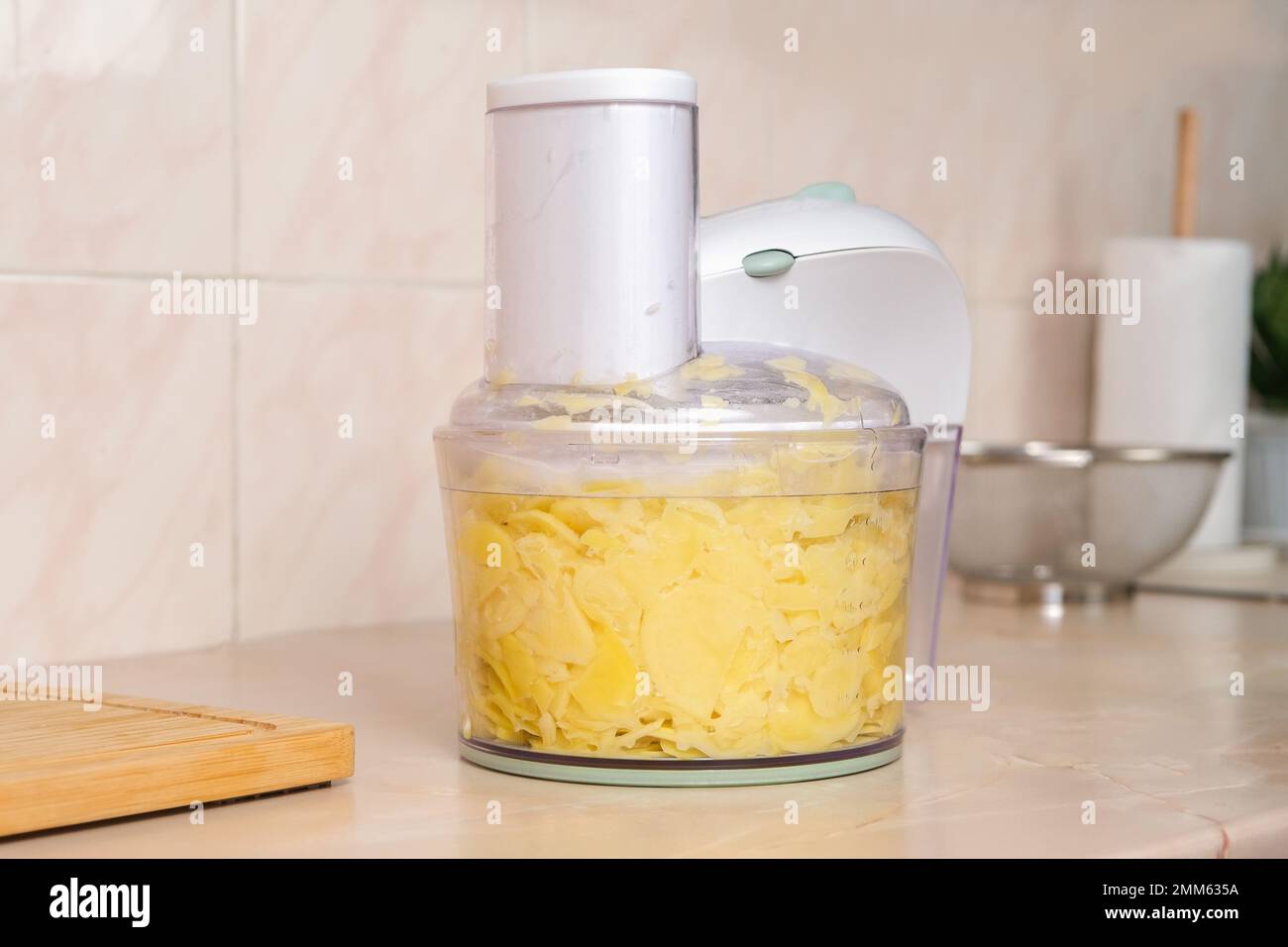Pommes de terre coupées en fines tranches dans le robot ménager. Préparation des pommes de terre pour la cuisson. Cuisine maison pour la famille. Processeur de cuisine. Assistants dans la cuisine. Accélération et facilitation de la cuisson du robot ménager Banque D'Images