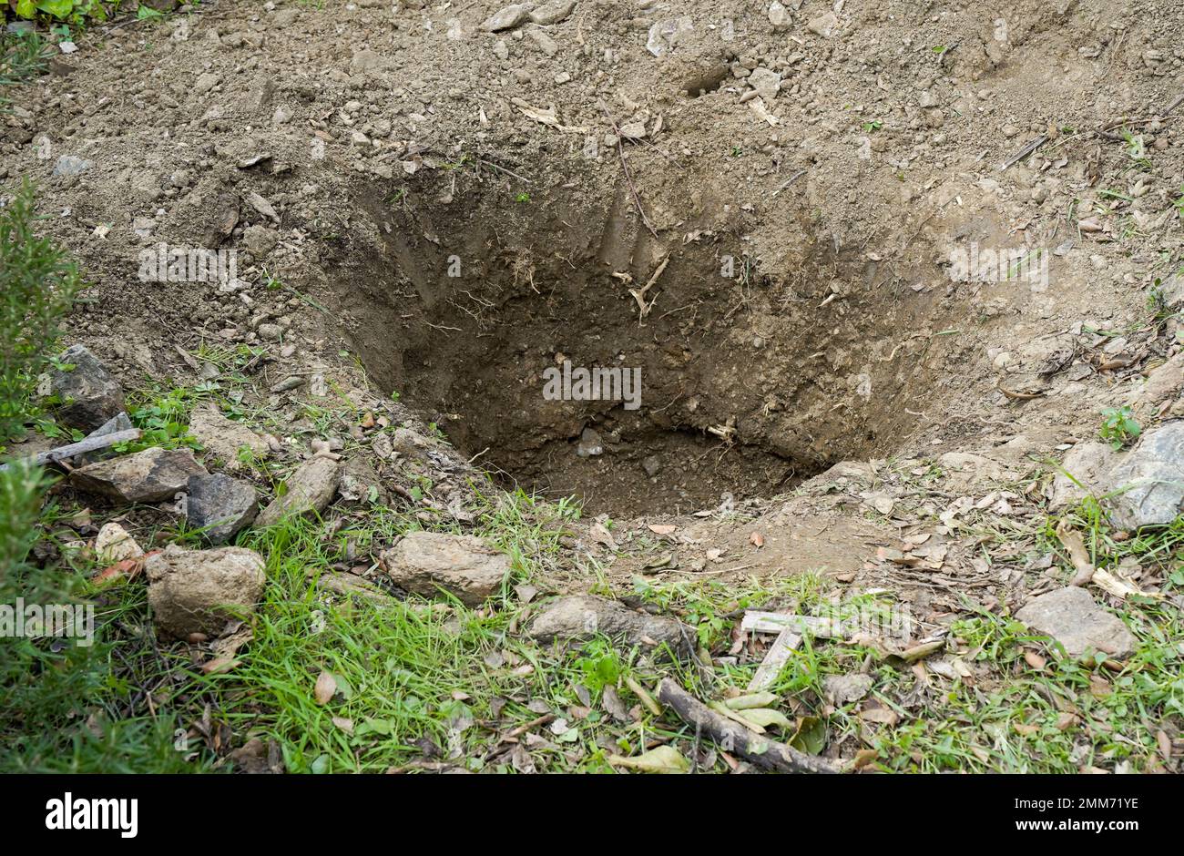 Trou profond dans le sol dans un jardin. Banque D'Images