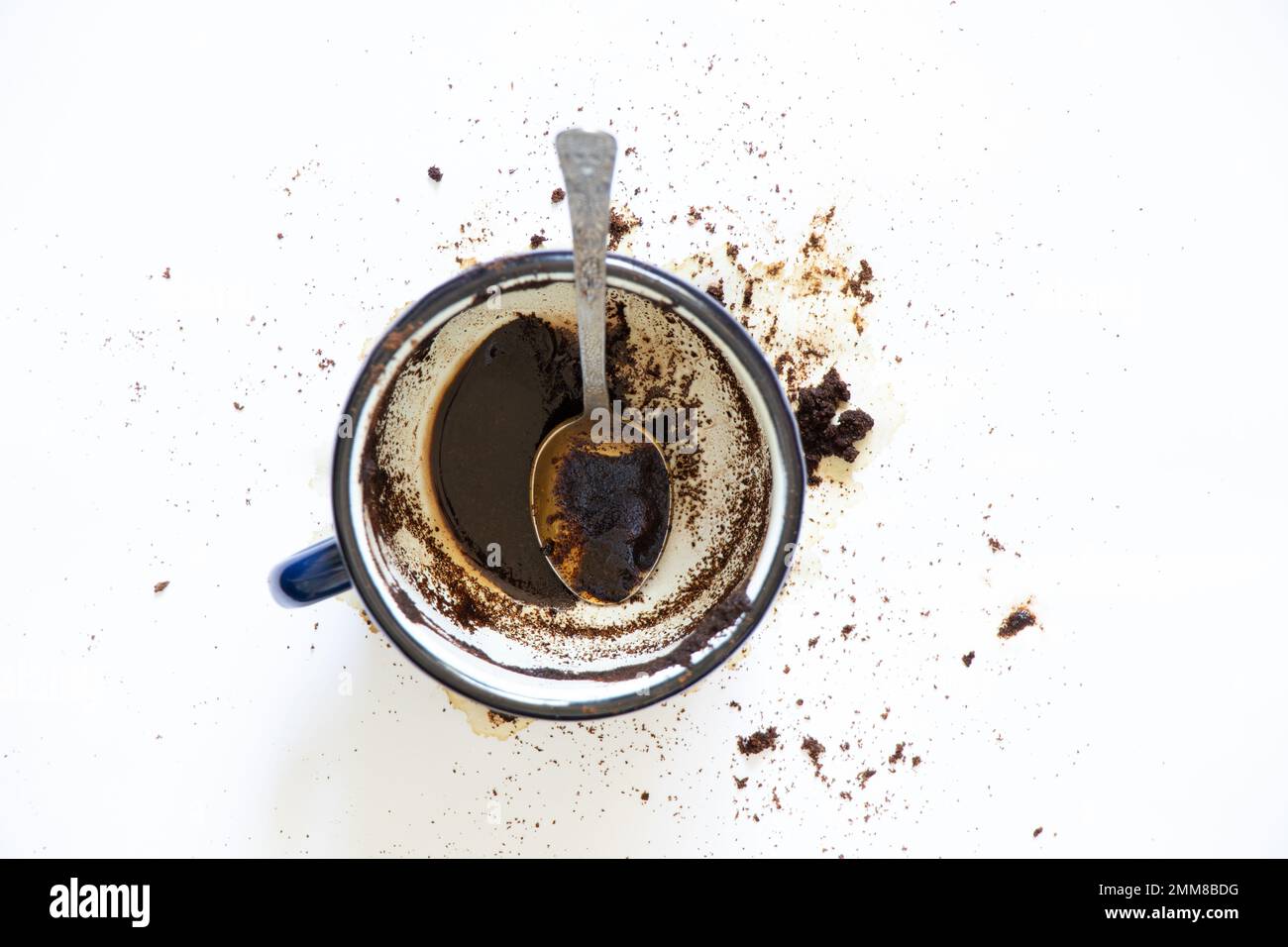 une tasse de café renversé sur un fond blanc et une cuillère à café se trouve à côté, du café renversé sur un fond blanc Banque D'Images