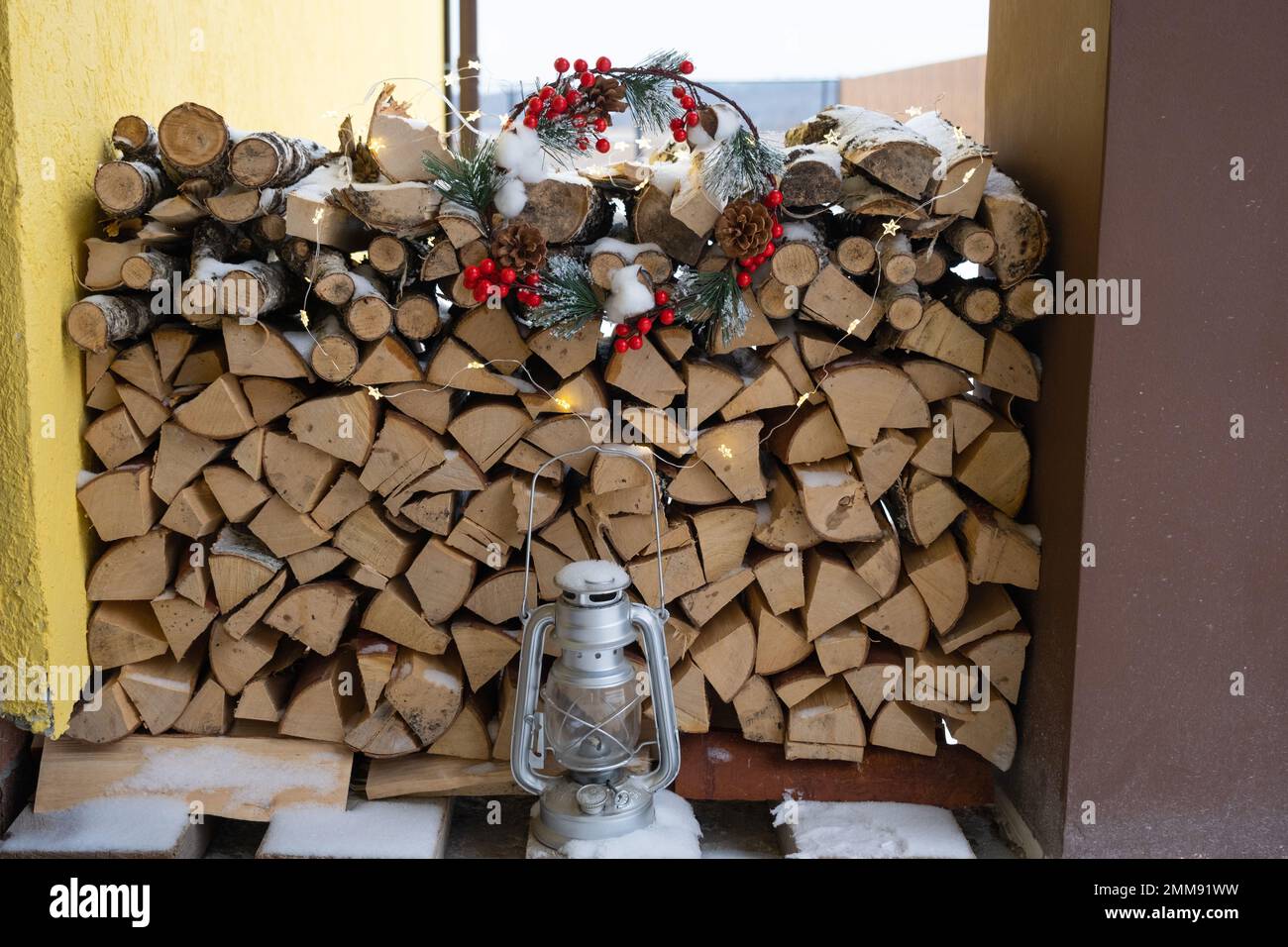 Le bois de chauffage sur le porche enneigé de la maison est récolté pour l'hiver. Chauffage du logement avec un foyer de poêle, économie d'électricité et de gaz dans un c Banque D'Images