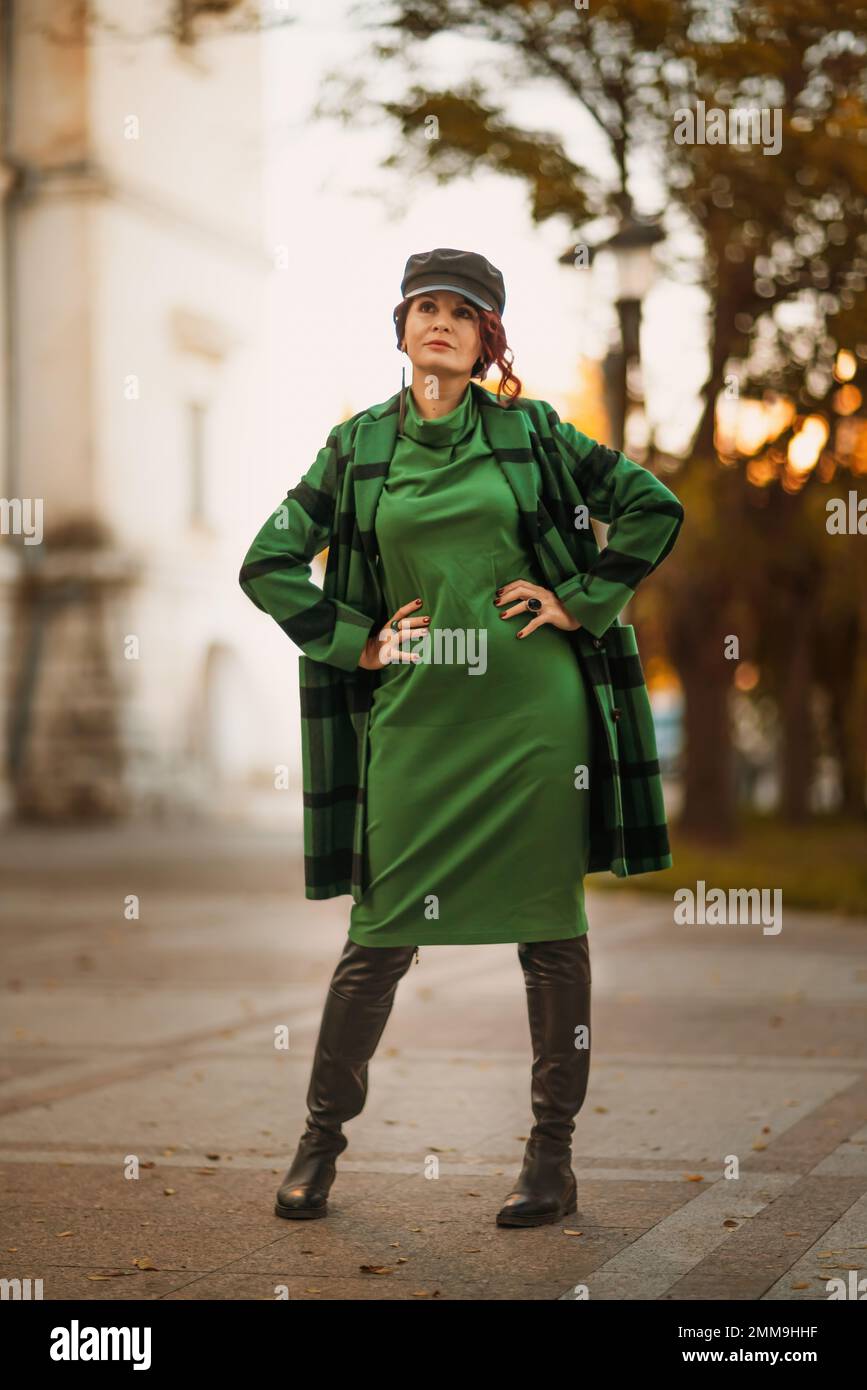 Portrait de mode en plein air d'une élégante femme brune tendance, modèle  dans une casquette élégante, robe verte, posant au coucher du soleil dans  une ville européenne en automne Photo Stock -