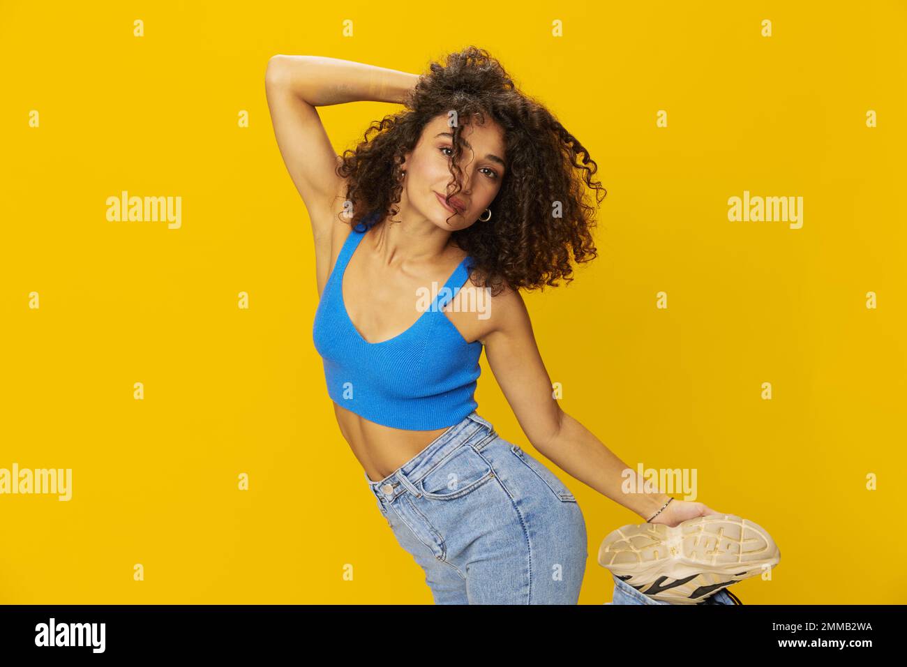 Femme aux cheveux bouclés afro dans un t-shirt bleu. signes de fond jaune avec ses mains, regarder dans la caméra, sourire avec les dents et le bonheur, copier Banque D'Images