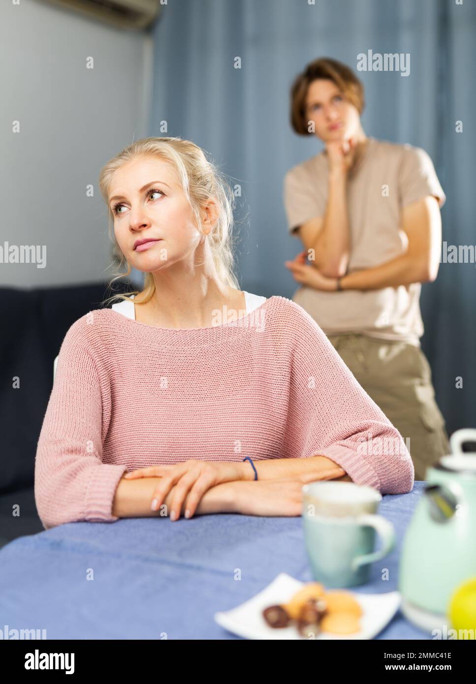 Femme contrariée assise à la table dans la cuisine Banque D'Images