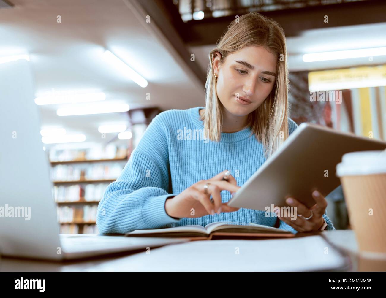 Éducation, université et femme en bibliothèque avec tablette, recherche et livres pour le projet ou l'examen scolaire. Ordinateur portable, ordinateur portable et Internet, étudiant Banque D'Images