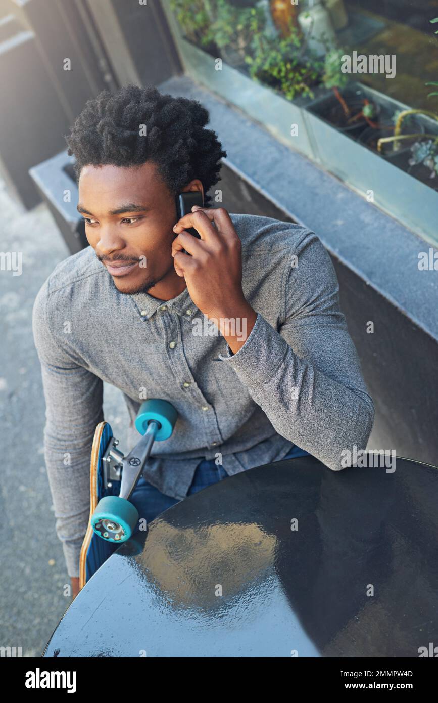 C'est bien, dude. un jeune patineur qui parle au téléphone dans un café-terrasse. Banque D'Images