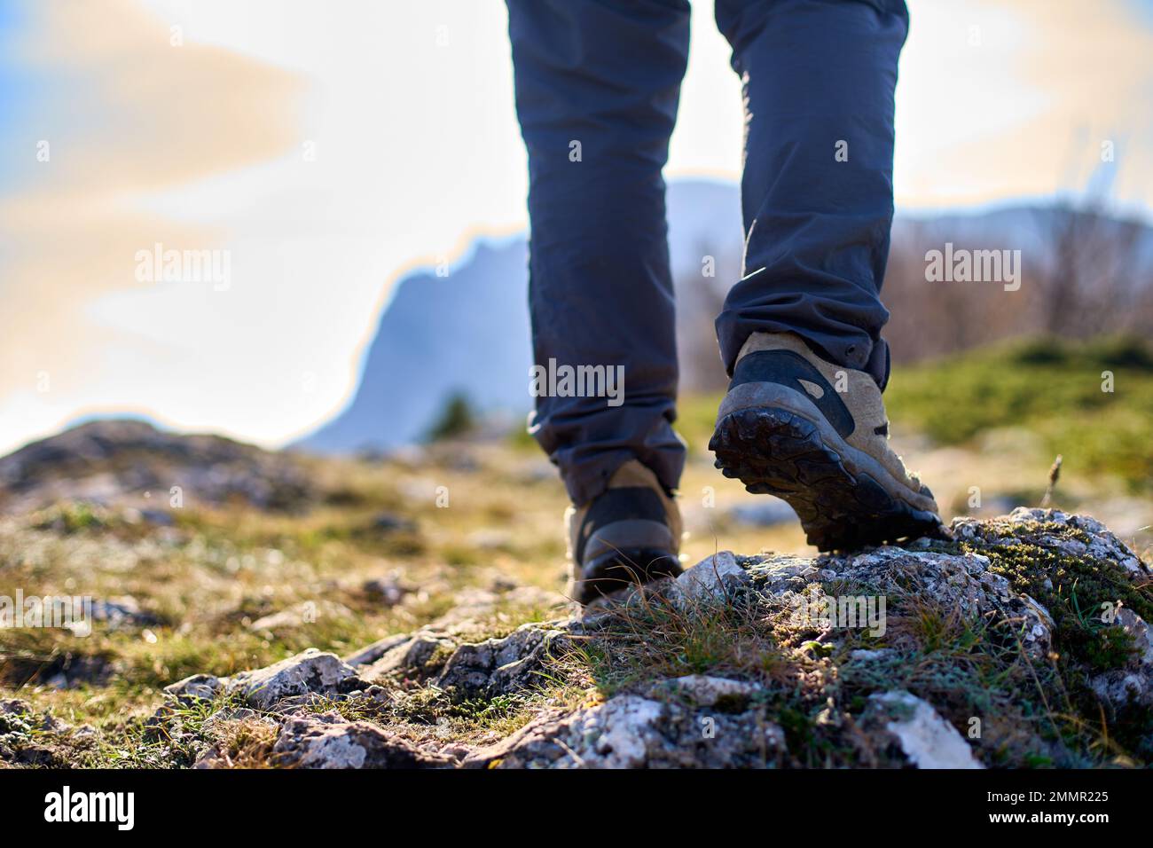 Jambes d'un randonneur dans des bottes de trekking marchant dans les montagnes gros plan. Pieds de touristes marchant portant des chaussures de randonnée sur une route rocheuse capturée de Banque D'Images