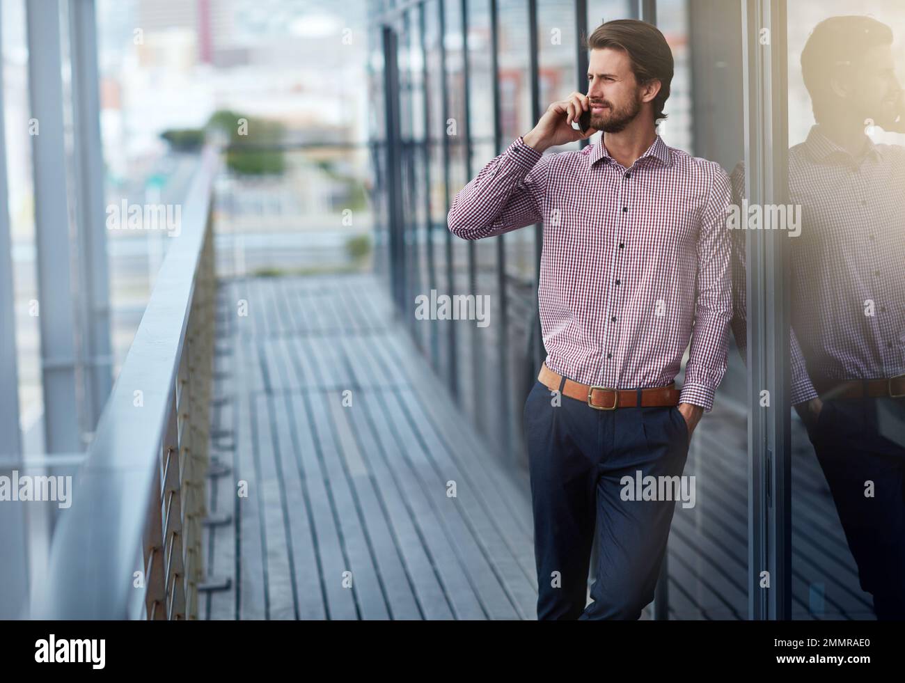 Rester en contact avec son réseau d'entreprise. un jeune homme d'affaires parlant au téléphone à l'extérieur d'un immeuble de bureaux. Banque D'Images