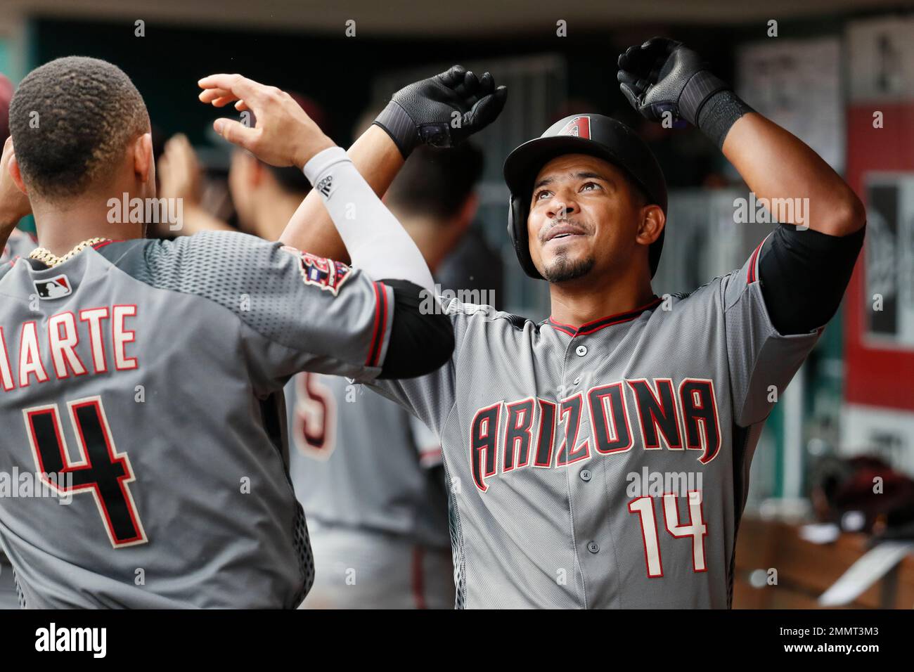 Arizona Diamondbacks' Eduardo Escobar (14) celebrates with Ketel Marte (4) in the dugout after hitting a two-run home run off Cincinnati Reds relief pitcher Keury Mella in the ninth inning of a baseball game, Sunday, Aug. 12, 2018, in Cincinnati. (AP Photo/John Minchillo) Banque D'Images