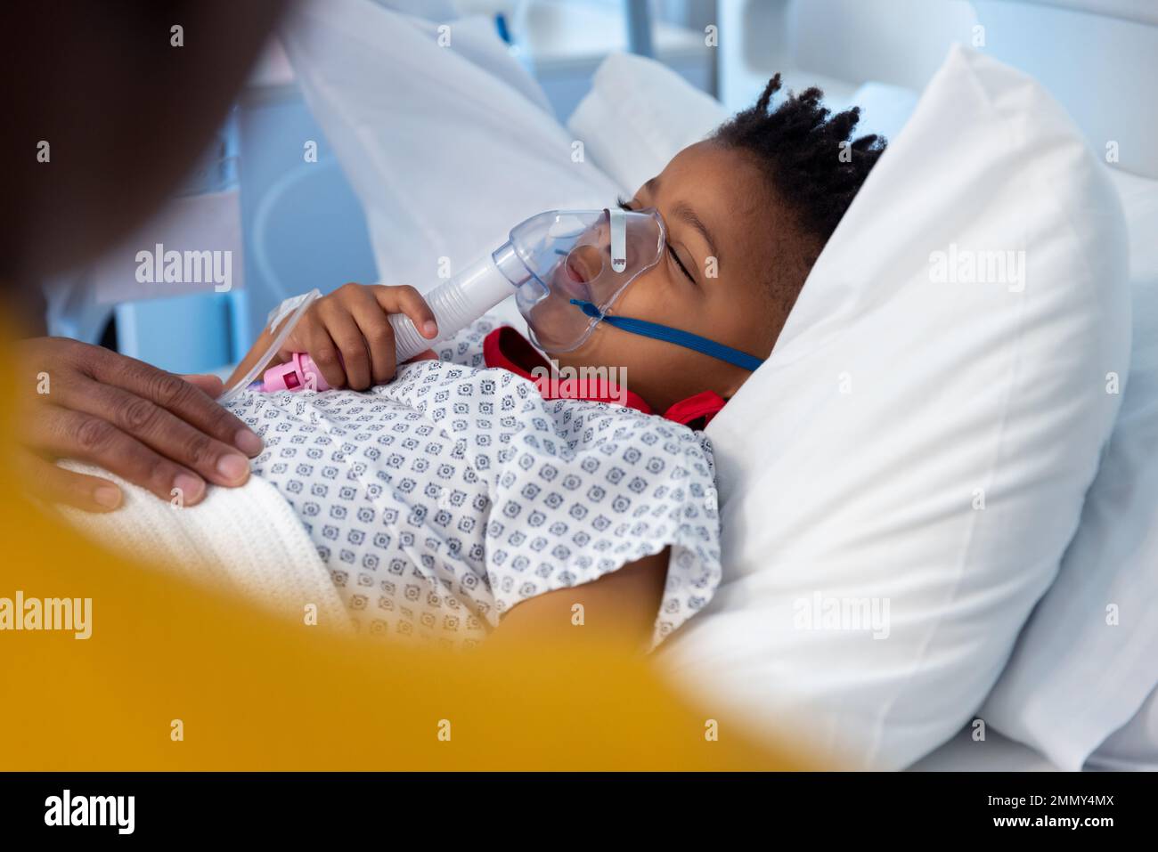 Garçon afro-américain endormi dans le lit d'hôpital portant un masque de ventilation Banque D'Images