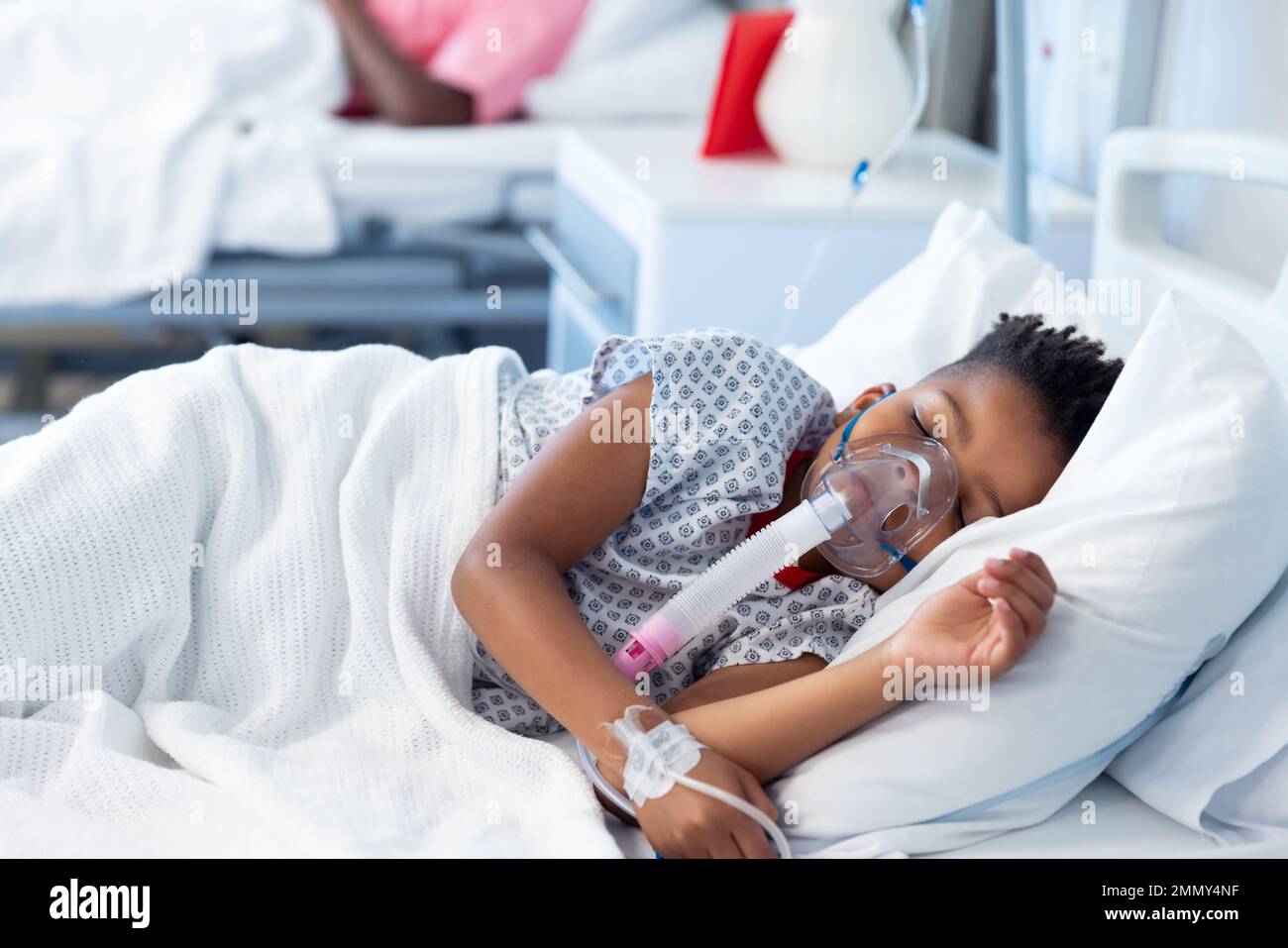 Un garçon afro-américain sous ventilation endormi dans un lit d'hôpital avec espace de copie Banque D'Images