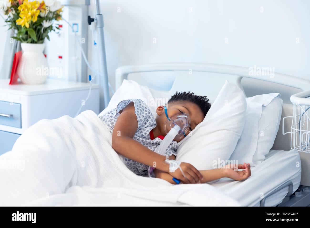 Un garçon afro-américain sous ventilation endormi dans un lit d'hôpital avec espace de copie Banque D'Images