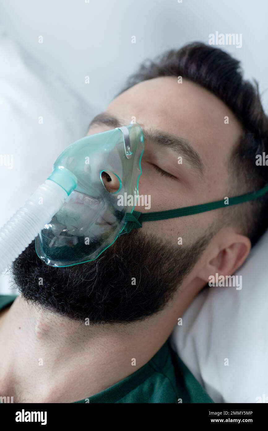 Un homme caucasien allongé au lit avec un masque à oxygène à l'hôpital Banque D'Images