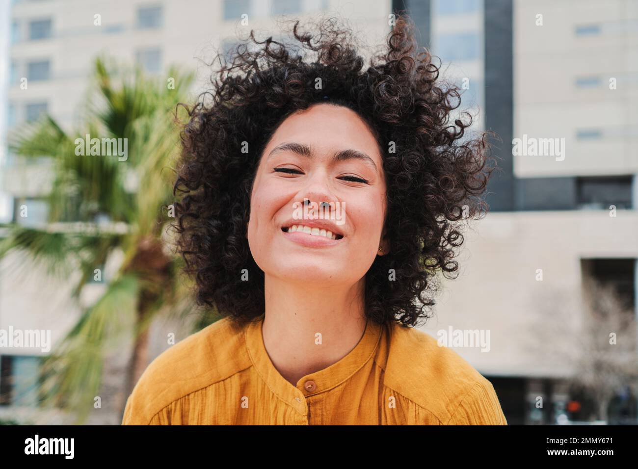 Vue de face de la jeune femme hispanique heureuse souriant avec des cheveux bouclés gros plan portrait de la dame cratie riant et s'amusant. Photo de haute qualité Banque D'Images