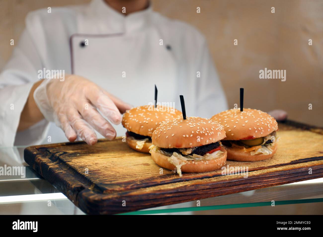 Employé de cantine d'école avec hamburgers à la ligne de service, clôture. Nourriture savoureuse Banque D'Images