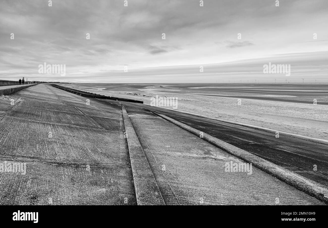Un sentier droit qui mène à la plage de Meols sur le Wirral capturé en noir et blanc en janvier 2023. Banque D'Images