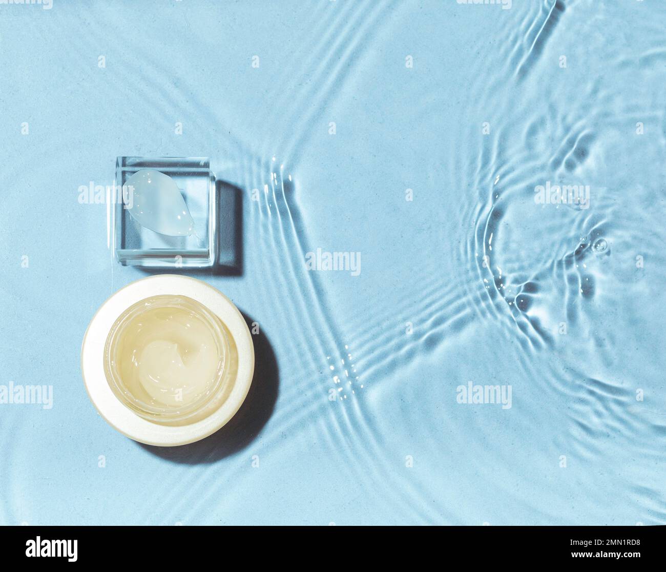 Nuance de crème sur podium en verre avec un pot sur fond d'eau. Concept de cosmétiques hydratants Banque D'Images