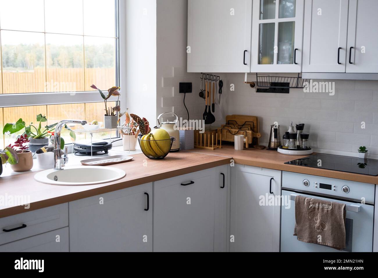 Cuisine blanche et confortable de style loft Scandi. Intérieur, design salle à manger, four, plaque de cuisson, table, mobilier de cuisine Banque D'Images