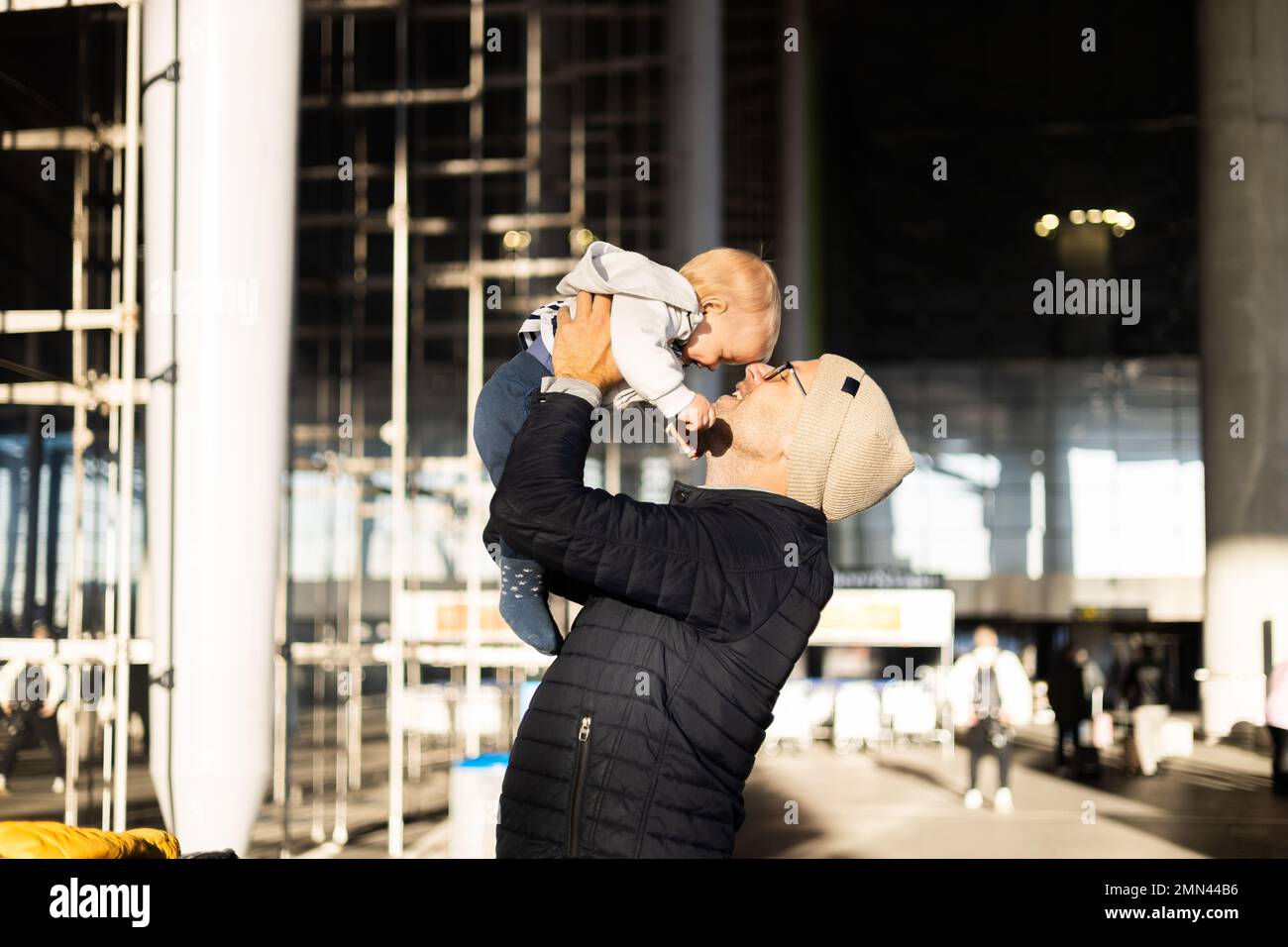 Le père se fait un plaisir de tenir et de soulever son bébé garçon enfant dans les airs après avoir été réjunté devant la gare de l'aéroport. Concept de voyage pour bébé Banque D'Images