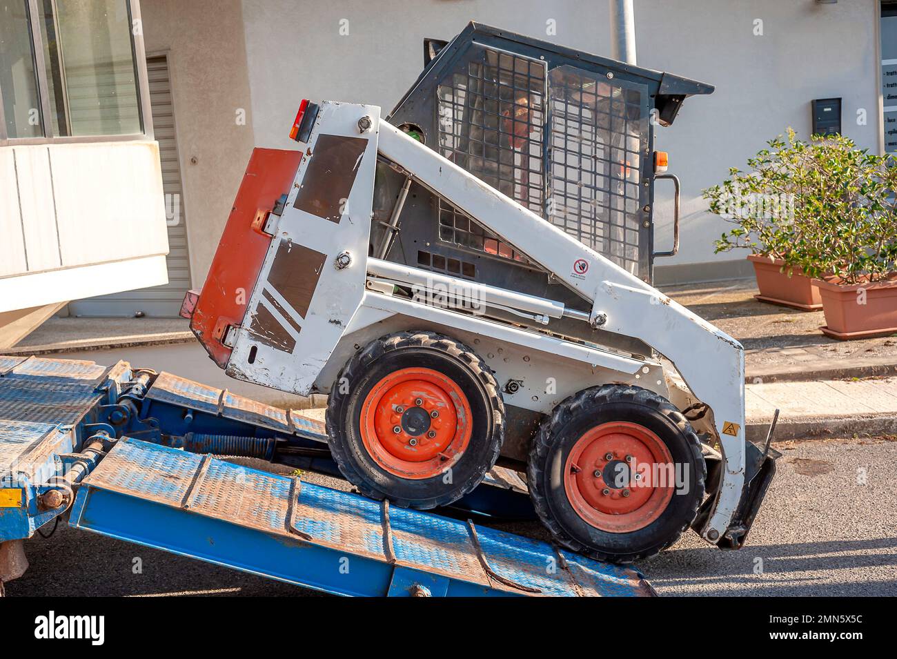 mini-excavatrice transportée sur le camion, au moyen de rampes, elle est déchargée par un opérateur Banque D'Images