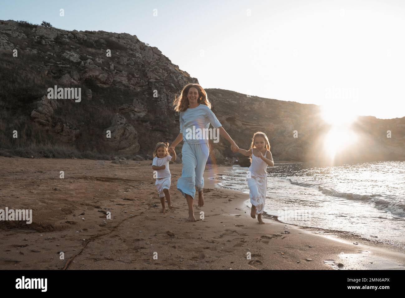 L'amour de la mère. Maman embrasse ses filles, embrasse et joue, tendresse et soin. Famille sympathique à la maison et en vacances. Banque D'Images