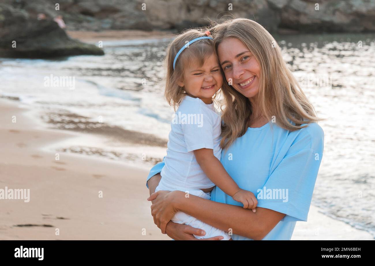 L'amour de la mère. Maman embrasse ses filles, embrasse et joue, tendresse et soin. Famille sympathique à la maison et en vacances. Banque D'Images