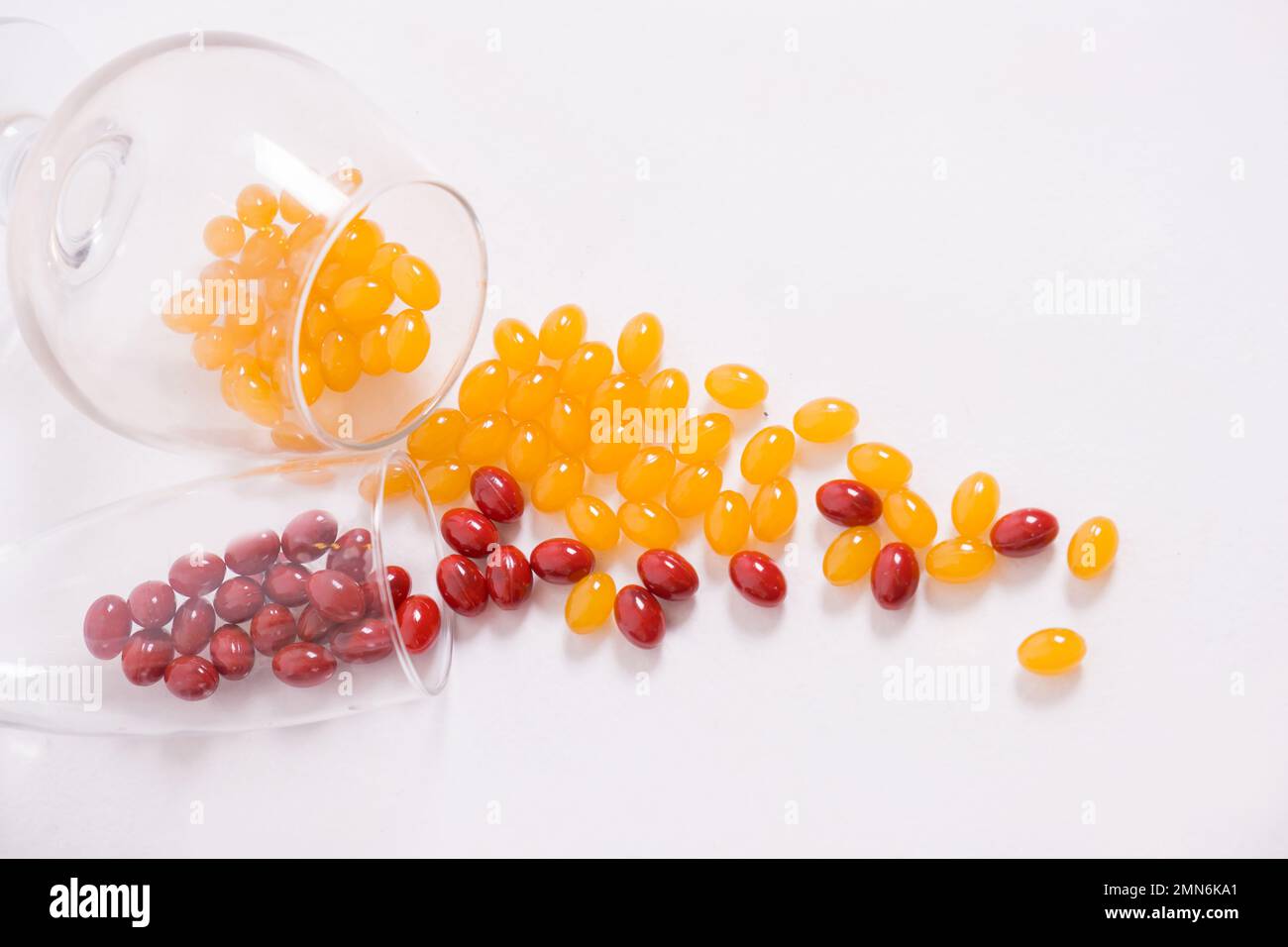 Comprimés, capsules pour la vision. Les vitamines rouges et jaunes sont versées sur la table à partir du verre. Lentilles dioptries, myopie, myopie. Corps, coeur et os sains. Photo de haute qualité Banque D'Images