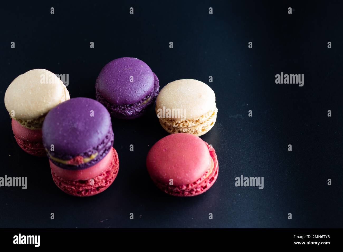 mini macaron de couleur différente sur fond sombre Banque D'Images